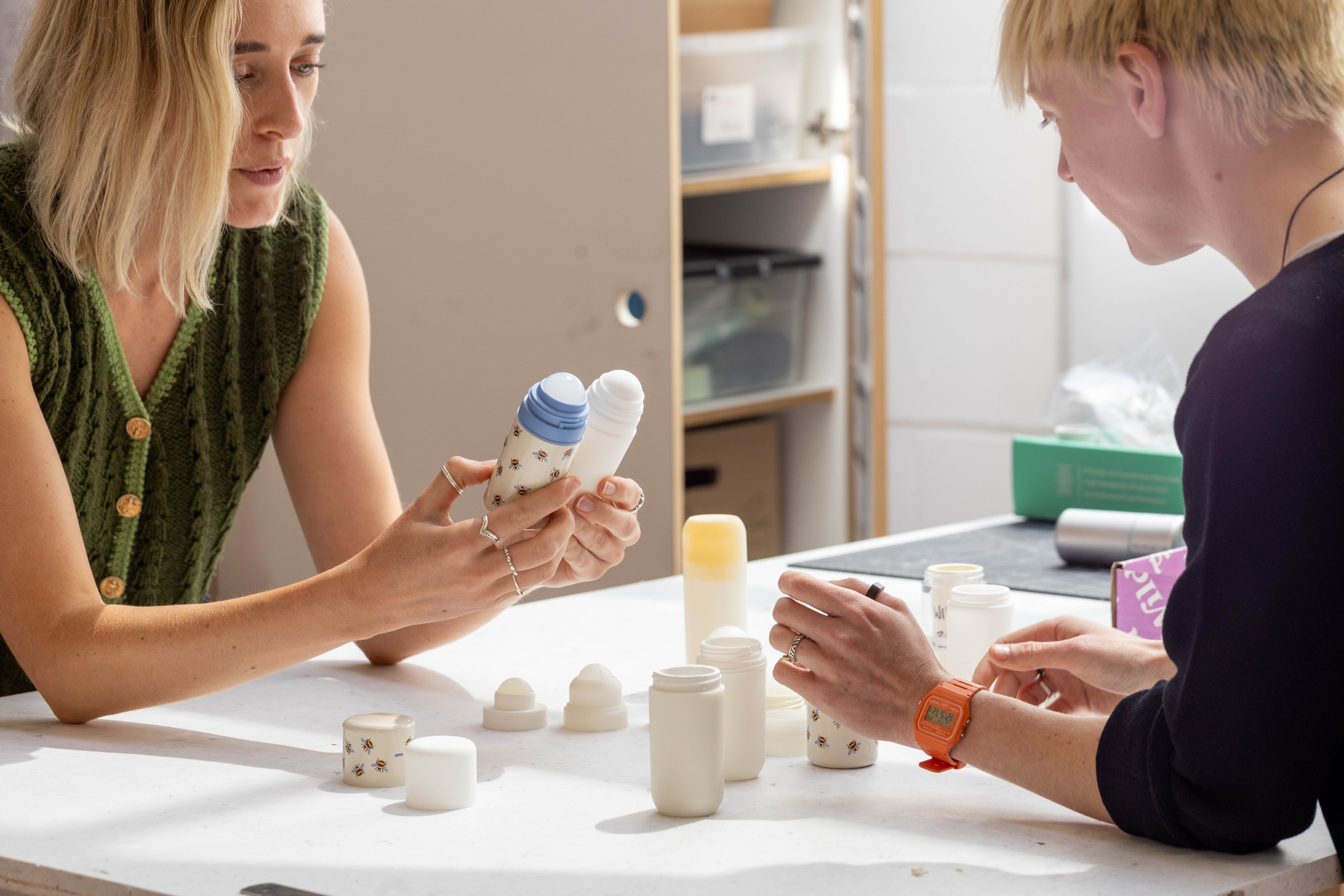two women discussing something holding up different products
