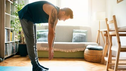 Man stretching over to touch his toes in his living room