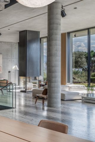 A living space with stone flooring, concrete pillar, and minimalist furniture