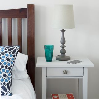 bedside white table with white lamp and green glass
