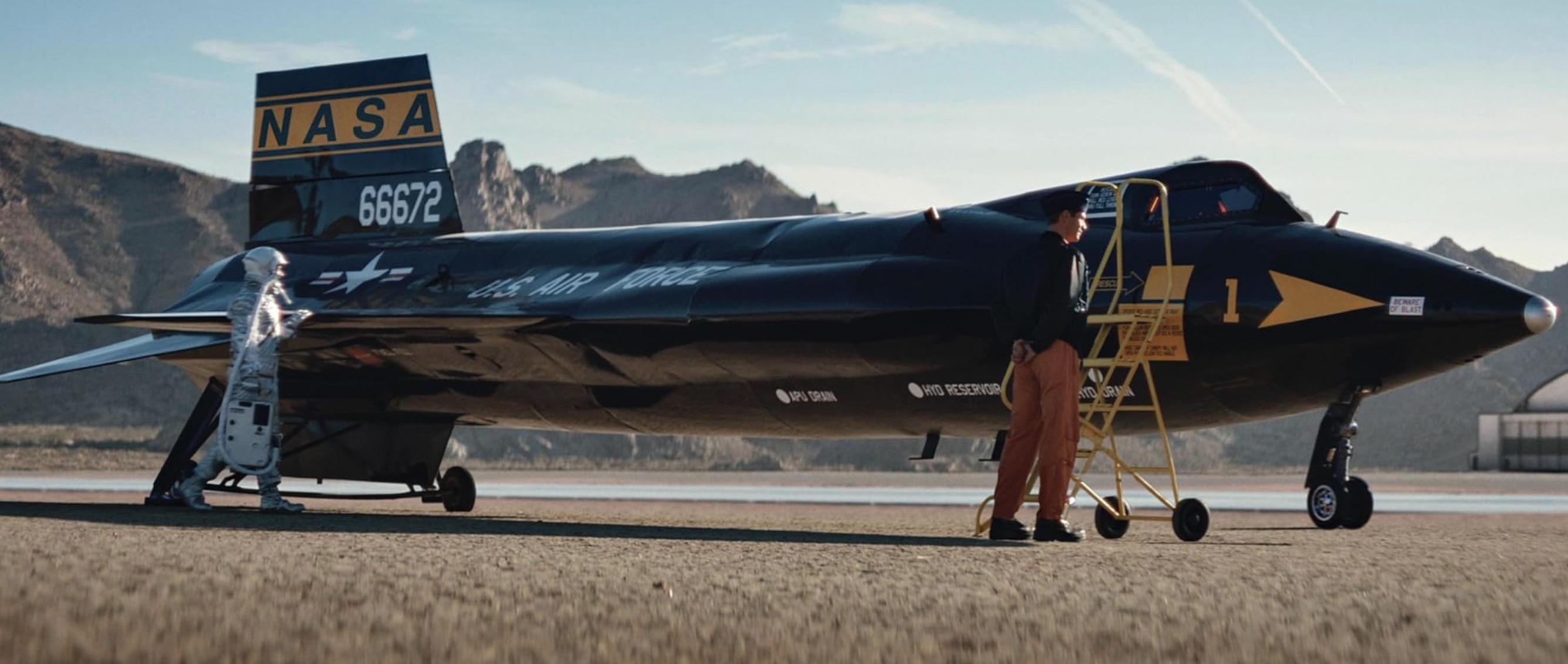 A sleek black spaceplane with a test pilot and crew member