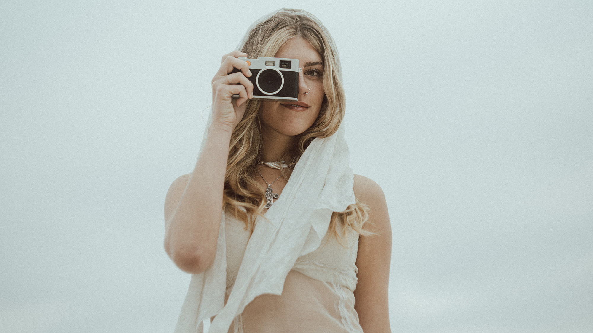 Person in white gown holding Echolens and looking through viewfinder 
