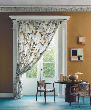 yellow dining room with French doors and single curtain, artwork on walls retro furniture