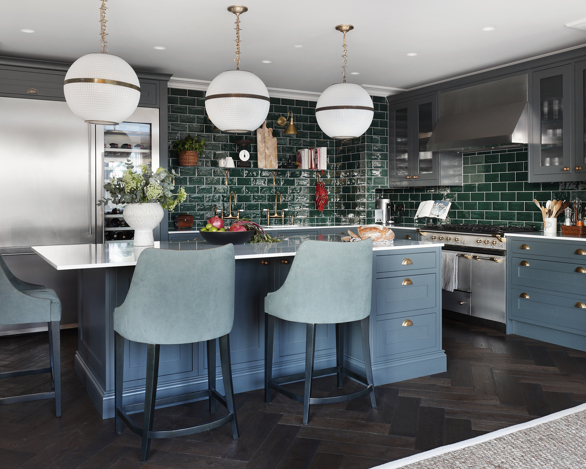 Kitchen with blue colored cabinets, dark green subway tiles and statement round pendant lighting.
