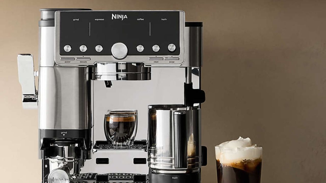 Ninja Luxe Café Pro Espresso Maker in silver against a neutral background next to a cold foam americano