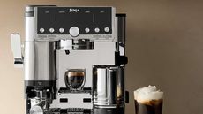 Ninja Luxe Café Pro Espresso Maker in silver against a neutral background next to a cold foam americano