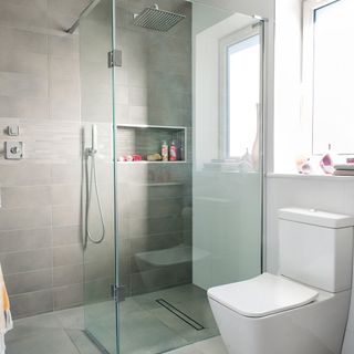 A glass shower cubicle with tiled wall and floor