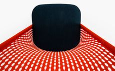 Looking down from above at a chair with a red mesh back, and a navy seat 