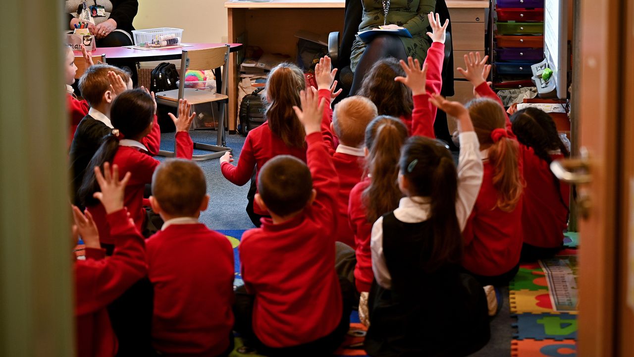 Children sitting on the floor in a classroom.