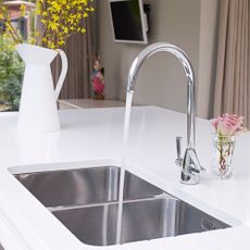 wash basin with faucet and white marble countertop with flower vase