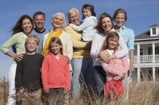 A wealthy family poses in front of their beach house.