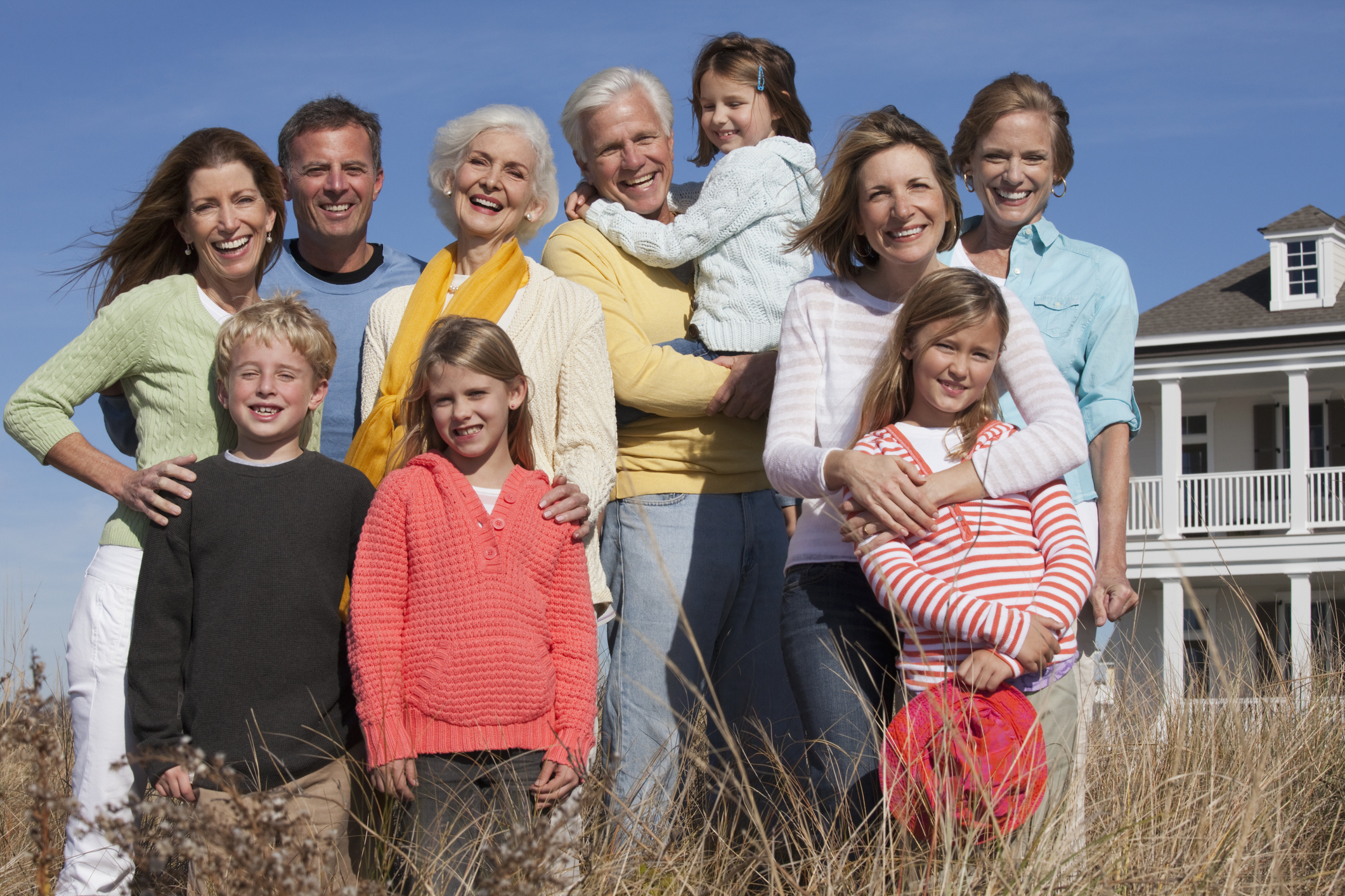 A wealthy family poses in front of their beach house.