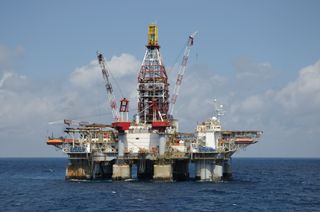 A free floating dynamically positioned semi-submersible deep water oil drilling platform on location in blue water. An off shore oil rig.