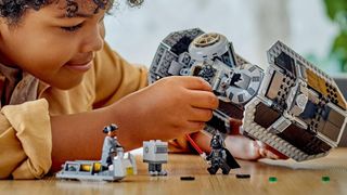 Kid playing with Lego TIE Bomber set