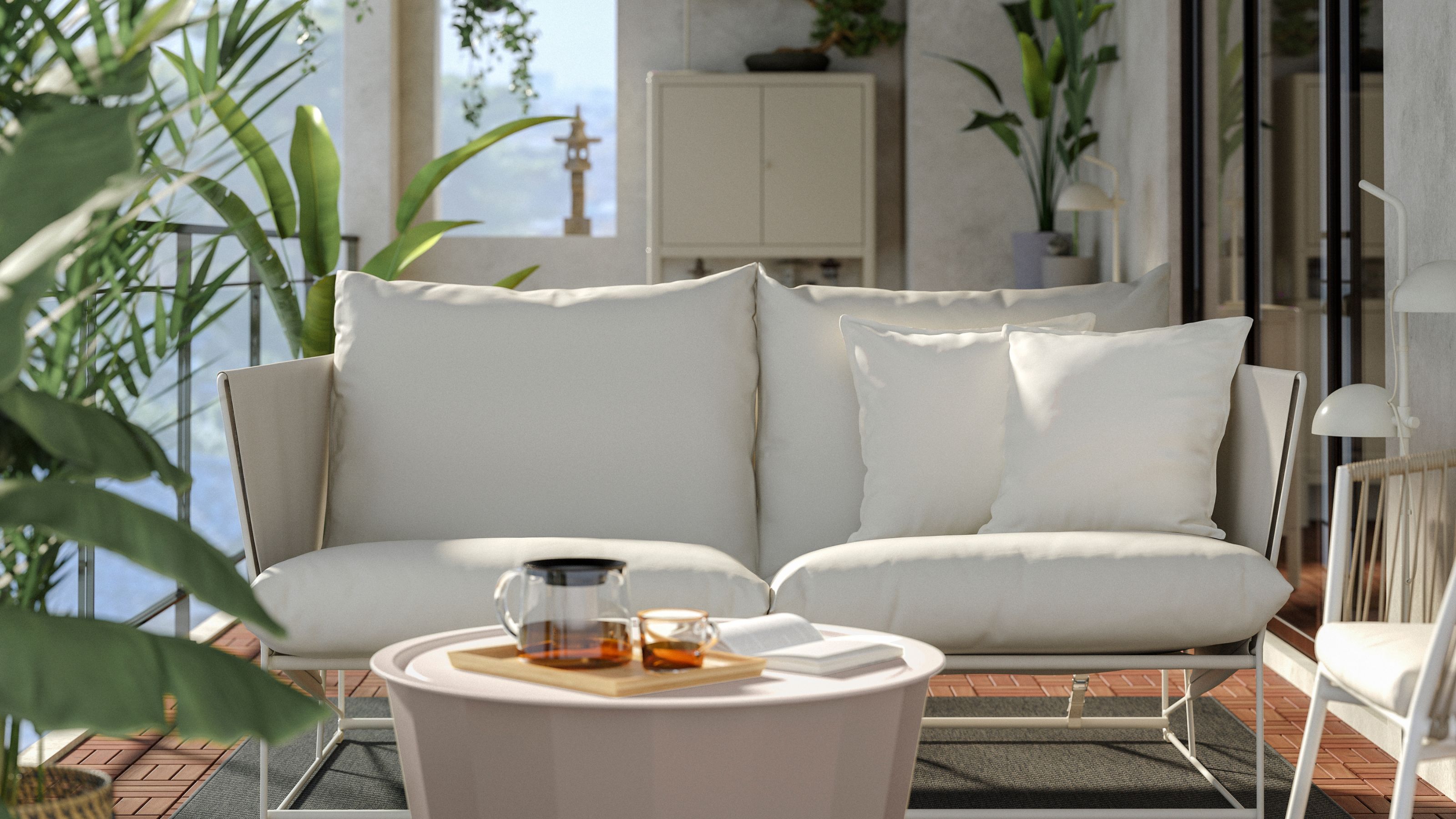 A two seat conversation set with a round coffee table on a balcony on top of a dark gray rug surrounded by foliage, with dark-framed sliding doors leading inside next to a garden closet