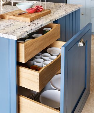 Kitchen drawers behind door in blue painted cabinet