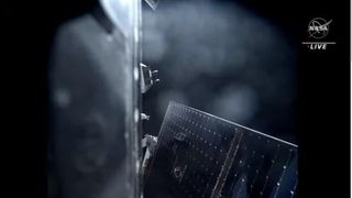 view of the side of a spacecraft and solar arrays in space