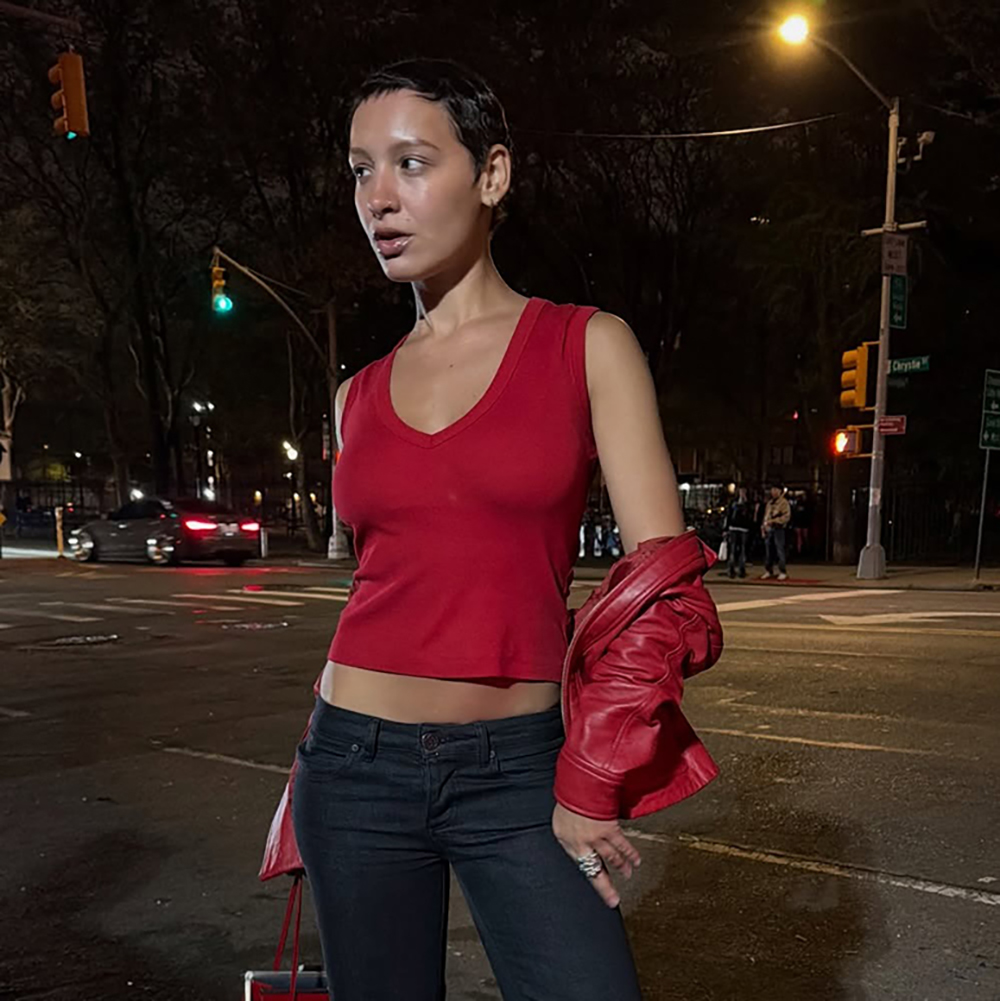 a woman wearing a red tank top, blue jeans, and red leather jacket