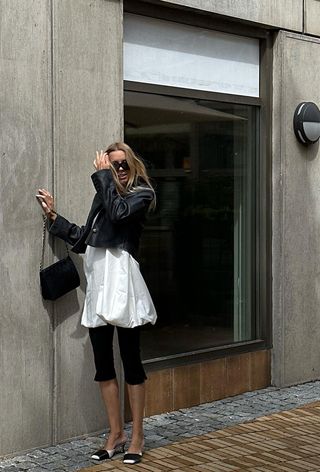 an influencer wearing a bubble hem dress with capri pants and leather jacket