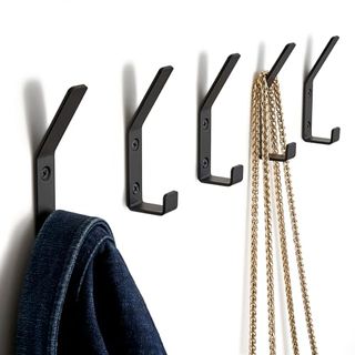 5 Black Metal Double Hooks on white wall. One has a dark blue denim jacket hanging, and the other has a handbag which has just gold chains visible