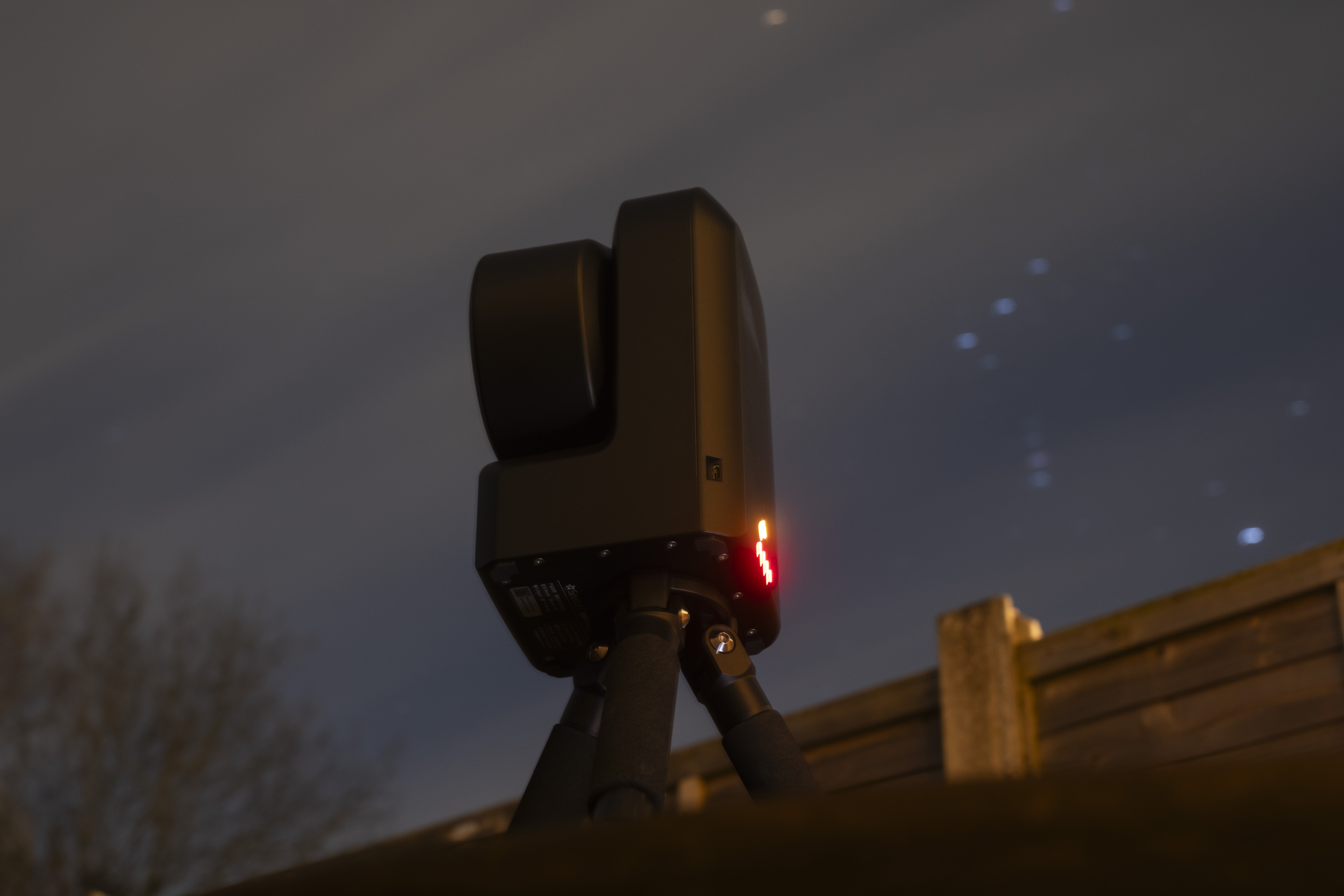 The ZWO Seestar S50 smart telescope in a garden in the night, with Orion constellation visible