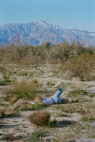 Image of a fallen figure on the ground with a mountainous backdrop