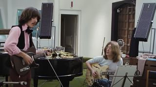 George Harrison (left) and John Lennon play the song Something in a scene from the 2021 film, Get Back