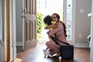 A woman dressed for work hugging a young girl