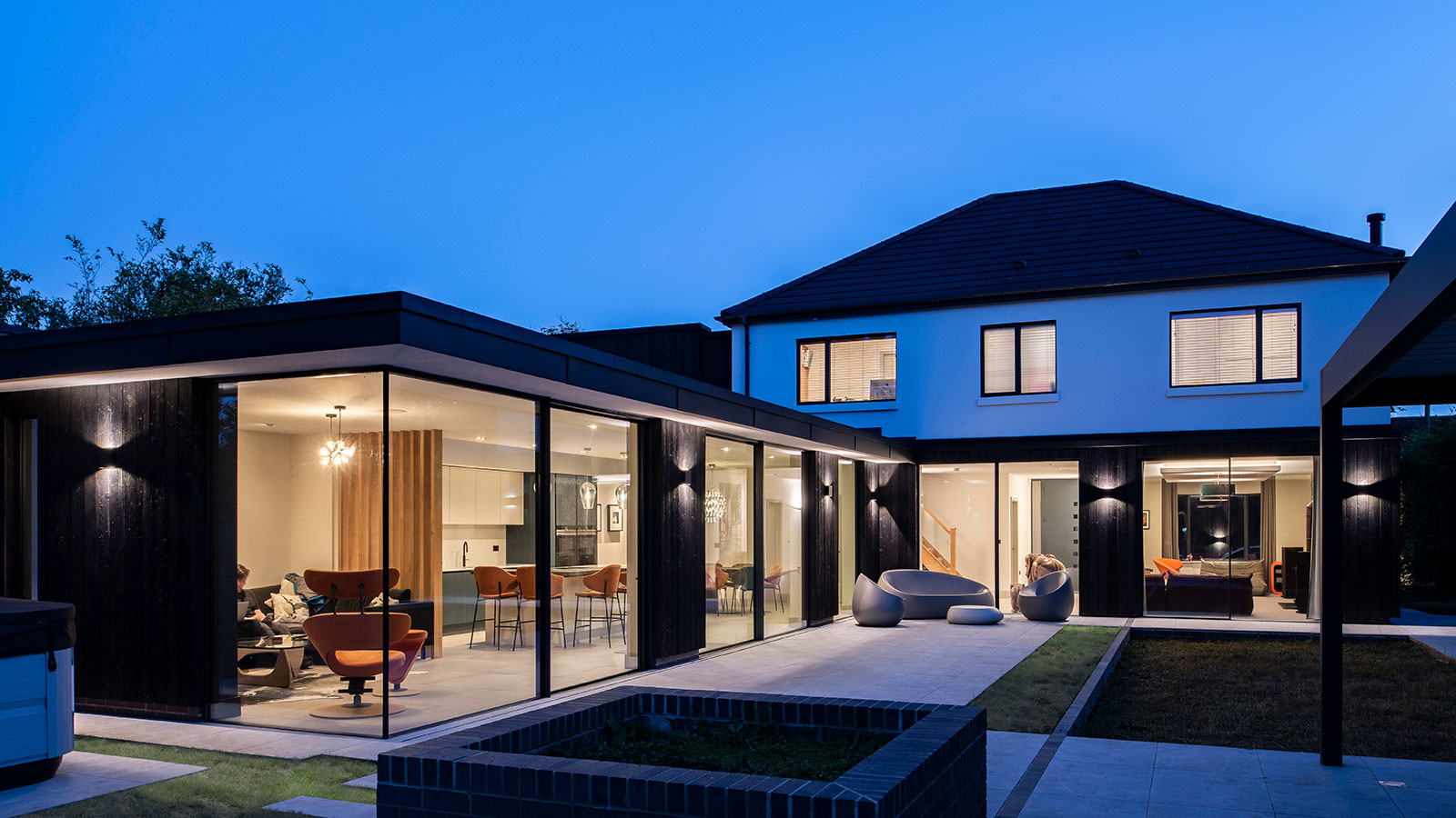 renovated and extended detached home at dusk with lights on inside the home