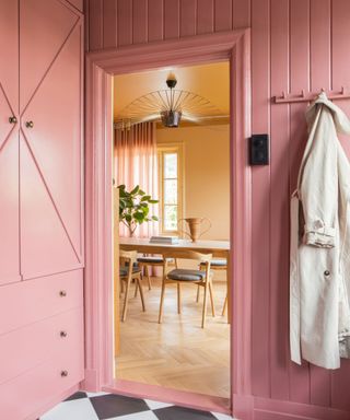 pink built ins in entrance with coat hooks and cupboard