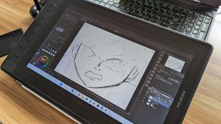 Huion Kamvas Pro 13 2.5K graphics / drawing tablet being used on a wooden table in an office space in the daytime.