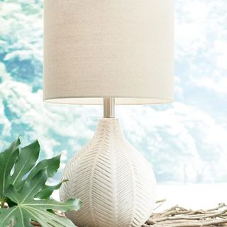 A sculptural table lamp with a white shade