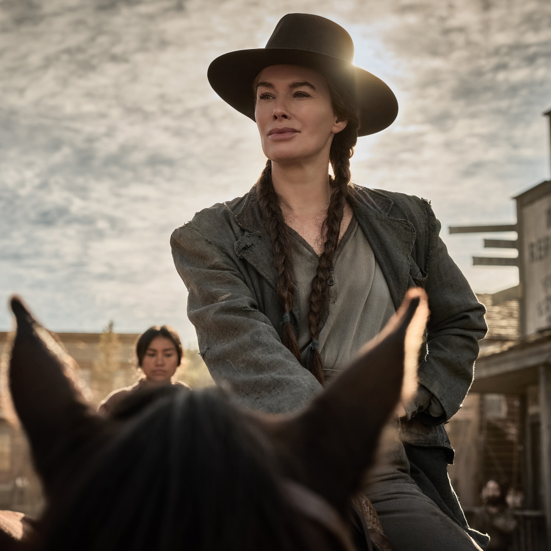 Lena Headey as Fiona Nolan wearing braids and a cowboy hat riding on a horse in a western town square in a still from The Abandons