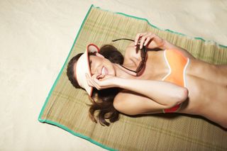 A woman sunbathing on a beach wearing an orange bikini.