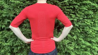 Rear view of man wearing red short-sleeved base layer by hedge