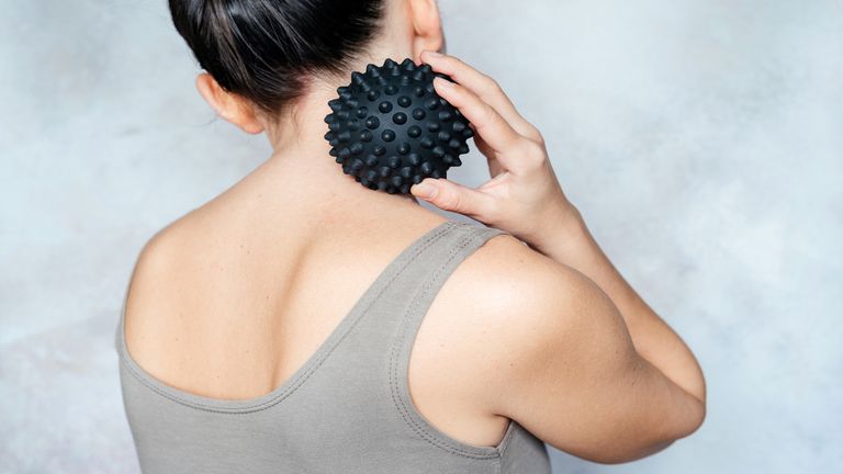 woman using a massage ball on her neck