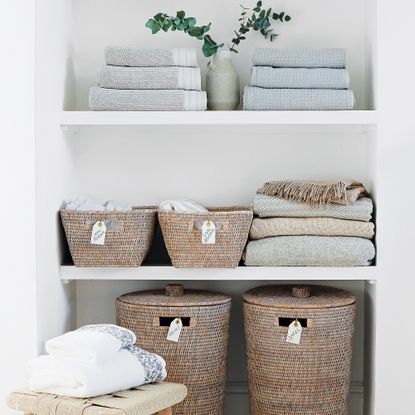 Open airing cupboard with labelled laundry baskets