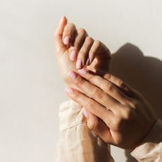 Image showing manicured hands with pink nail polish against an ivory background