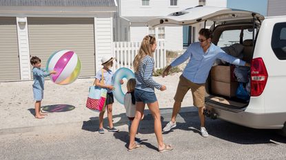A family unloads a car to go to a vacation rental house on the beach.