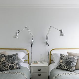 White bedroom with twin beds and wall hung lighting