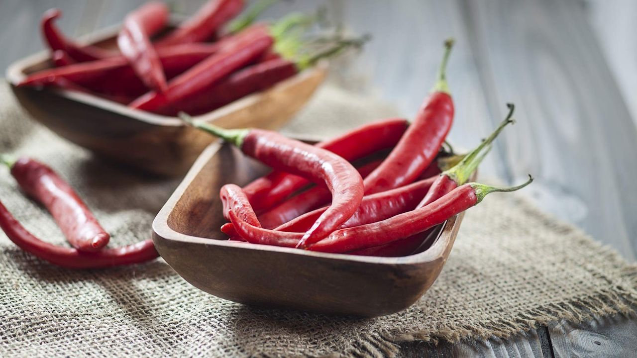 A bowl of red chili peppers on a wooden board