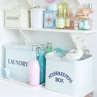 Laundry powder and cleaning brushes below shelf with various cleaning items