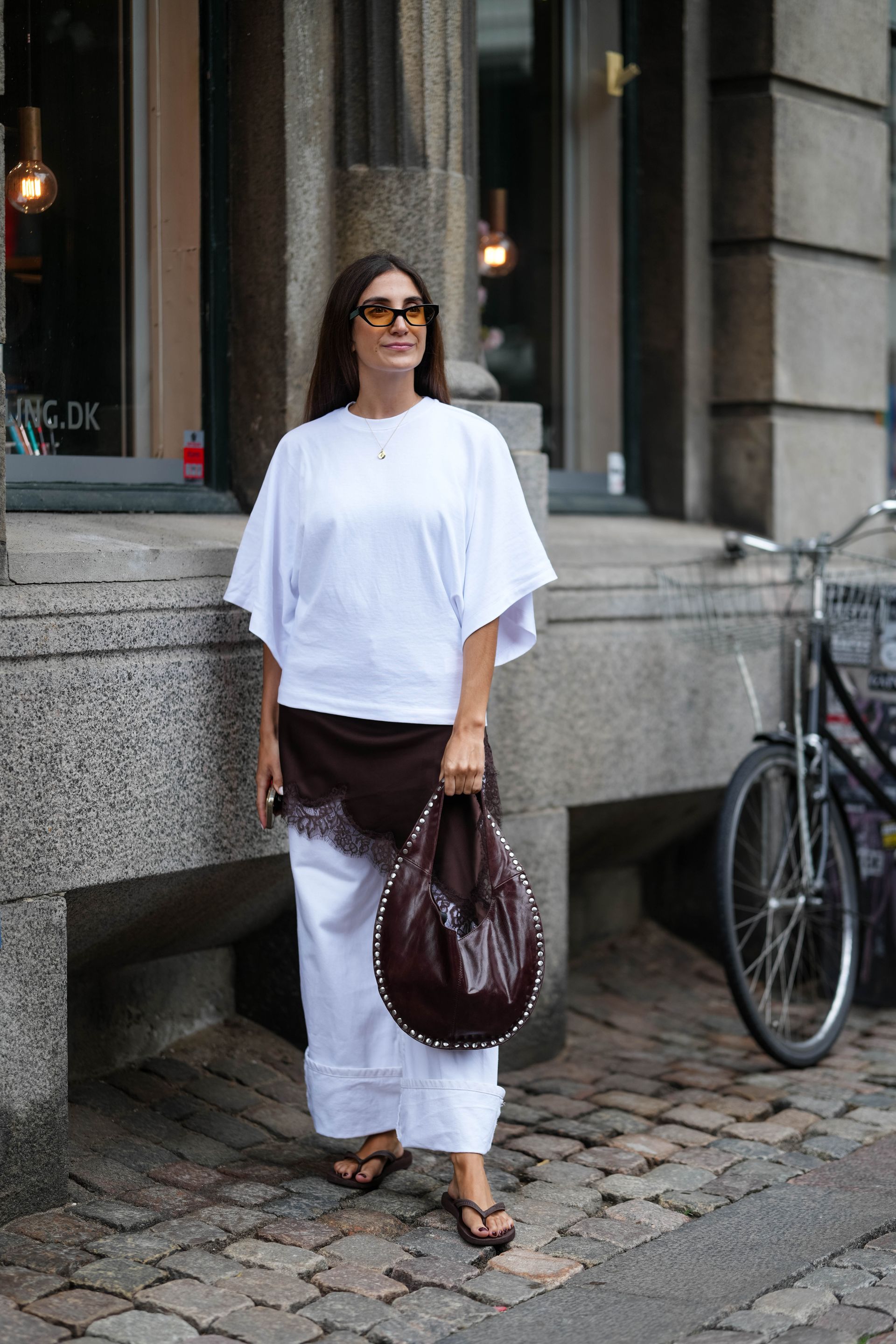 Woman wearing white t-shirt and white jeans with brown lace dress
