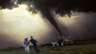 A promotional image for Twister showing two people running away from a giant tornado