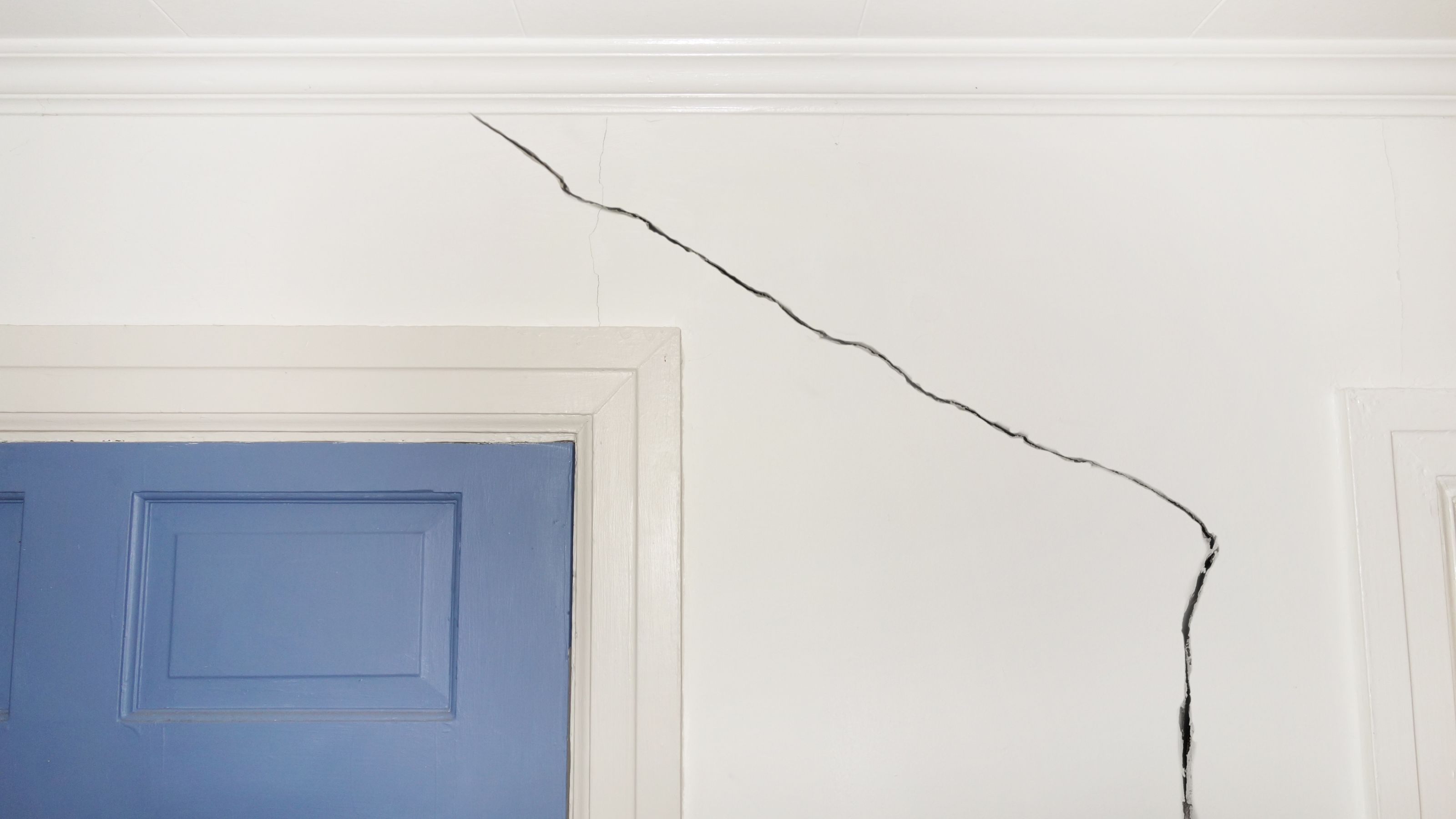 crack in wall near a blue door