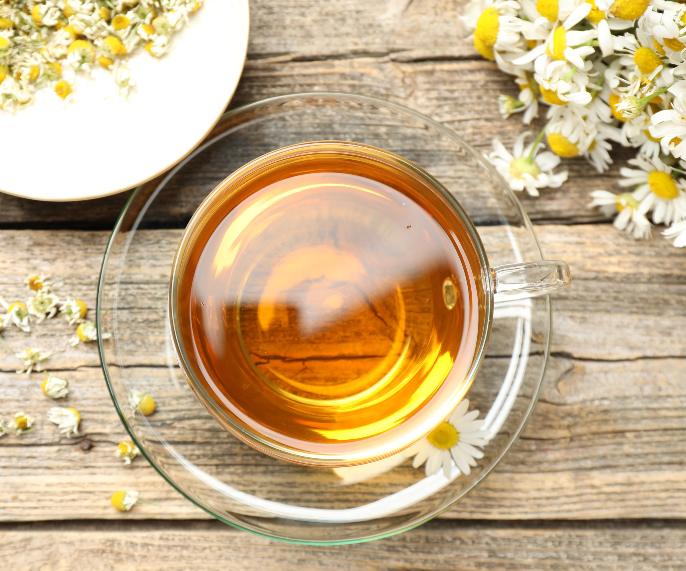 chamomile tea in glass cup with flowers on wooden table