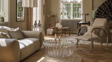 A neutral living room with Scandi style furniture and a crystal glass coffee table