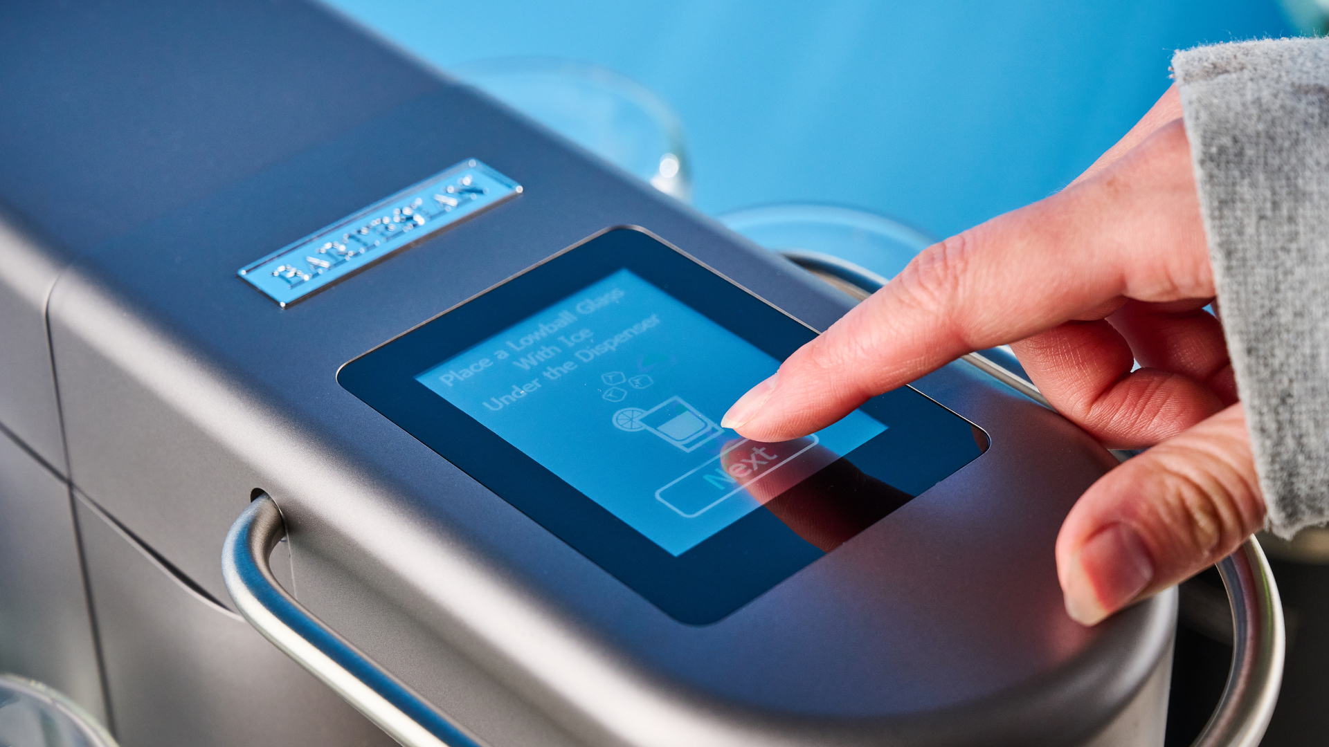 the bartesian premium cocktail machine photographed against a blue background showing its drink-making abilities and accessories and functionality with cocktail pods