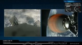 This still from a SpaceX webcast shows the Falcon 9 rocket's second stage engine nozzle (right) firing as it carries Dragon into orbit. Meanwhile, the a camera on the first stage booster shows grid-like control fins deployed for the return back to Earth.