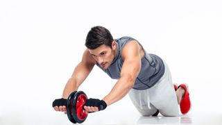 Man demonstrating how to do an ab wheel rollout on a white background